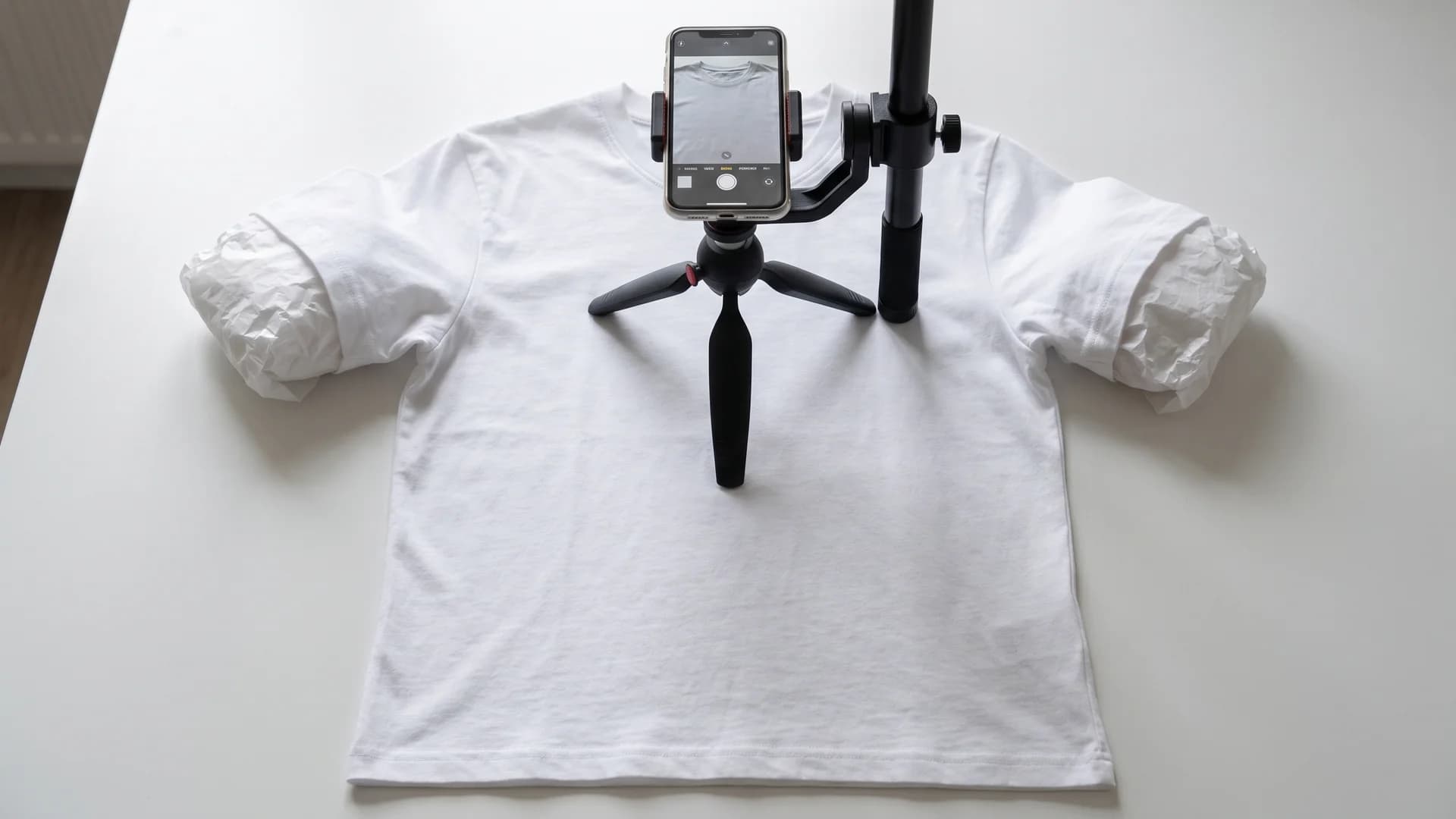 Flat-lay setup for a ghost mannequin photo without a model, a padded t-shirt shot straight down under window light