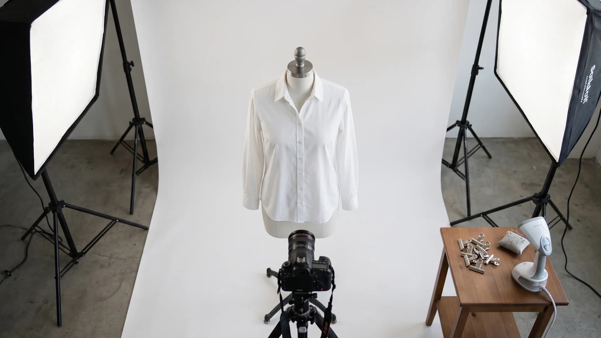 Ghost mannequin effect shoot setup with a matte white dress form, softbox lights, and a tripod-mounted camera